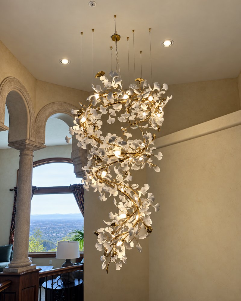 Ginkgo-leaf chandelier hung from multiple ceiling points in a two-story entry